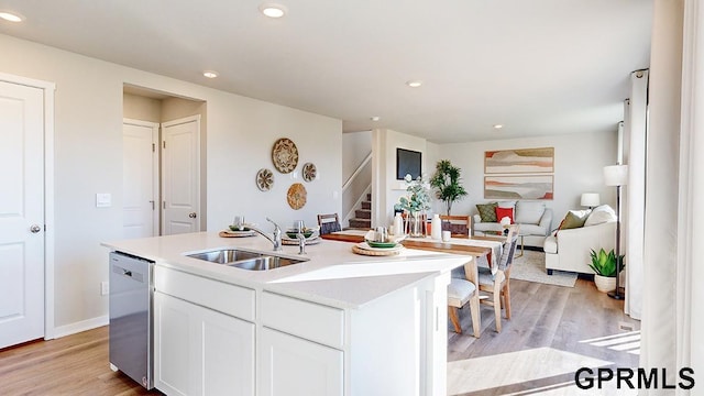 kitchen featuring stainless steel dishwasher, white cabinetry, sink, and a kitchen island with sink