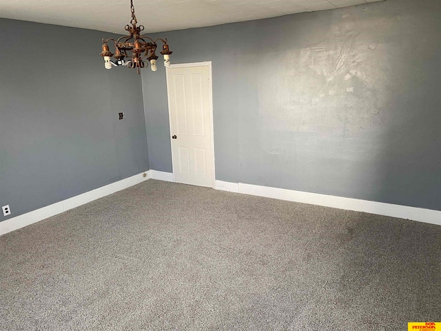 carpeted spare room featuring an inviting chandelier