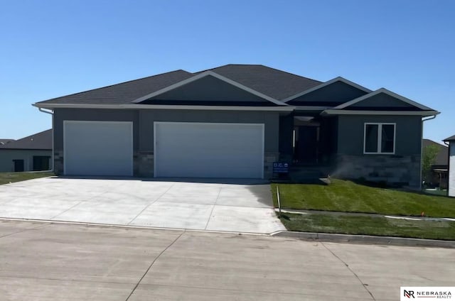 view of front facade with a garage, driveway, stone siding, and a front yard