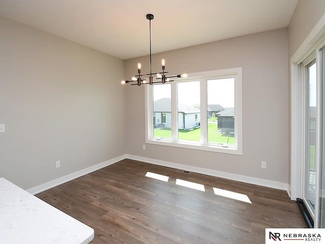 unfurnished dining area featuring a chandelier and dark hardwood / wood-style flooring