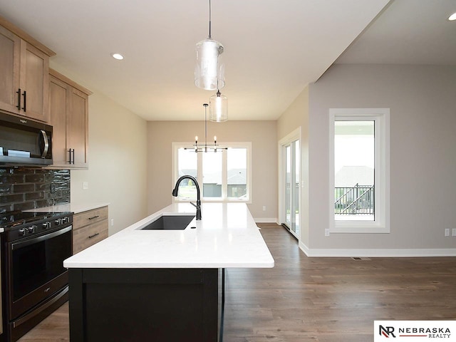 kitchen with a chandelier, black gas range oven, a kitchen island with sink, and sink