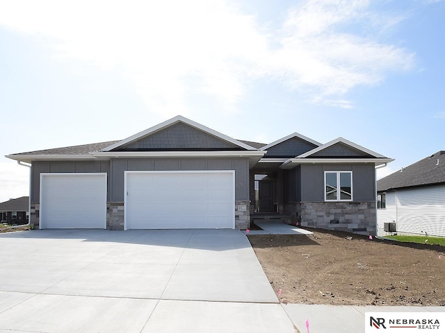 view of front of house featuring a garage, concrete driveway, stone siding, central air condition unit, and board and batten siding