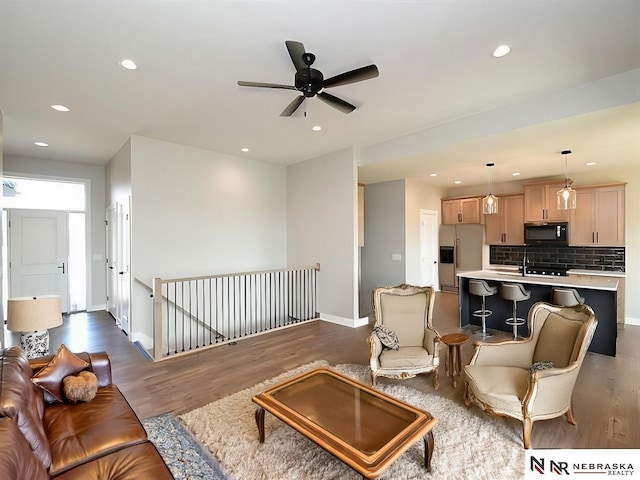 living area with baseboards, ceiling fan, wood finished floors, and recessed lighting