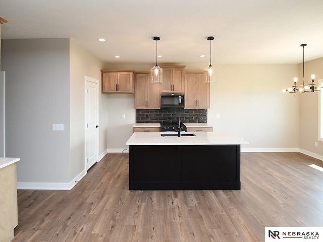 kitchen with pendant lighting, sink, hardwood / wood-style floors, and tasteful backsplash