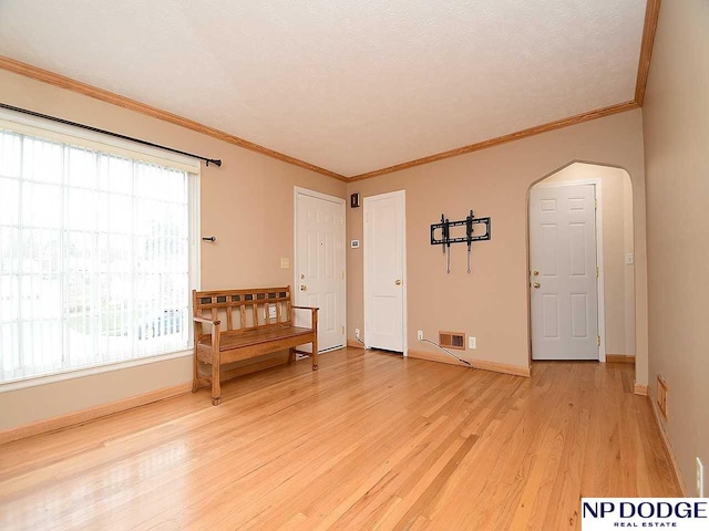 spare room with a textured ceiling, hardwood / wood-style flooring, and crown molding