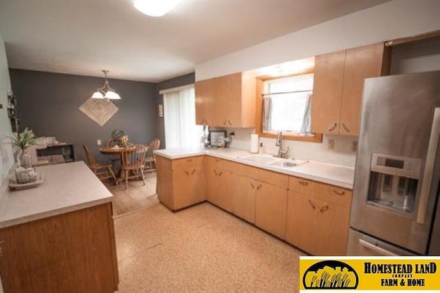 kitchen featuring light brown cabinets, sink, hanging light fixtures, stainless steel fridge, and a notable chandelier