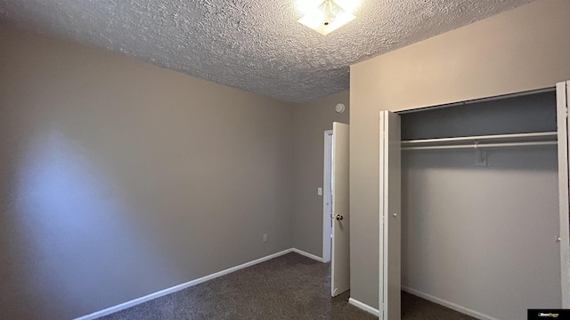 unfurnished bedroom featuring dark colored carpet, a textured ceiling, and a closet