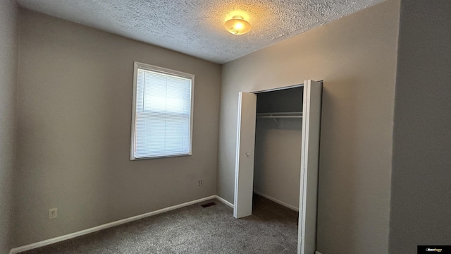 unfurnished bedroom featuring carpet flooring, a textured ceiling, and a closet