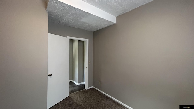 hall featuring a textured ceiling and dark carpet