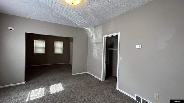 empty room featuring dark colored carpet and a textured ceiling