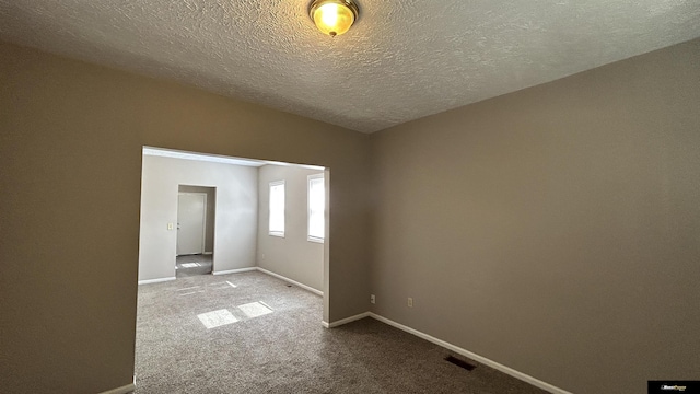 carpeted empty room with a textured ceiling