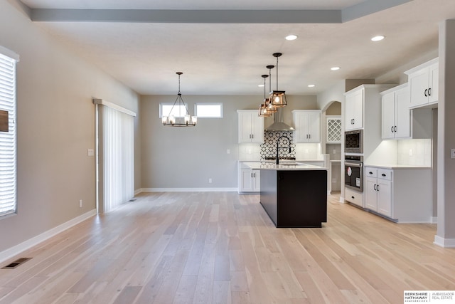 kitchen featuring white cabinets, decorative light fixtures, stainless steel appliances, and light hardwood / wood-style flooring