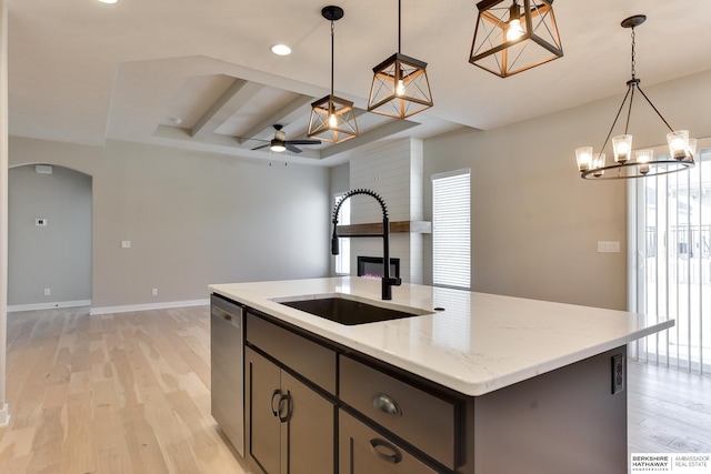 kitchen with sink, an island with sink, decorative light fixtures, ceiling fan with notable chandelier, and light wood-type flooring