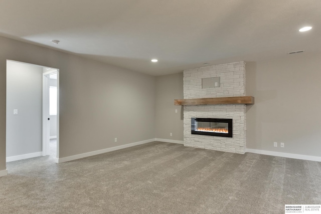 unfurnished living room featuring carpet and a stone fireplace