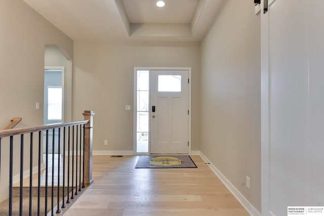 foyer featuring a raised ceiling and light hardwood / wood-style floors