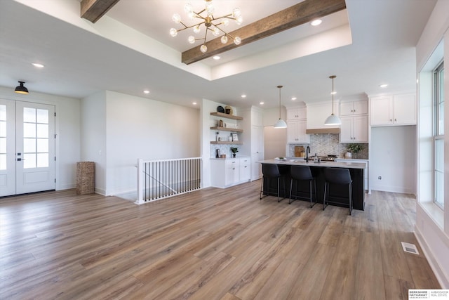 kitchen with light hardwood / wood-style flooring, white cabinets, a healthy amount of sunlight, and decorative light fixtures