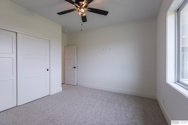 unfurnished bedroom featuring ceiling fan, a closet, and light carpet