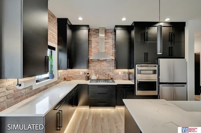 kitchen with stainless steel appliances, decorative light fixtures, light stone countertops, tasteful backsplash, and wall chimney exhaust hood