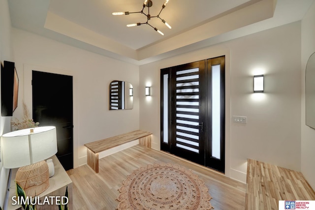 entryway with light hardwood / wood-style floors, a raised ceiling, plenty of natural light, and a notable chandelier