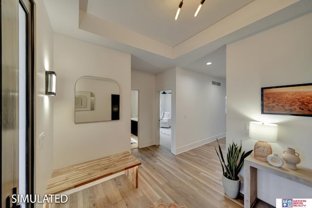 hall featuring a raised ceiling and light hardwood / wood-style flooring