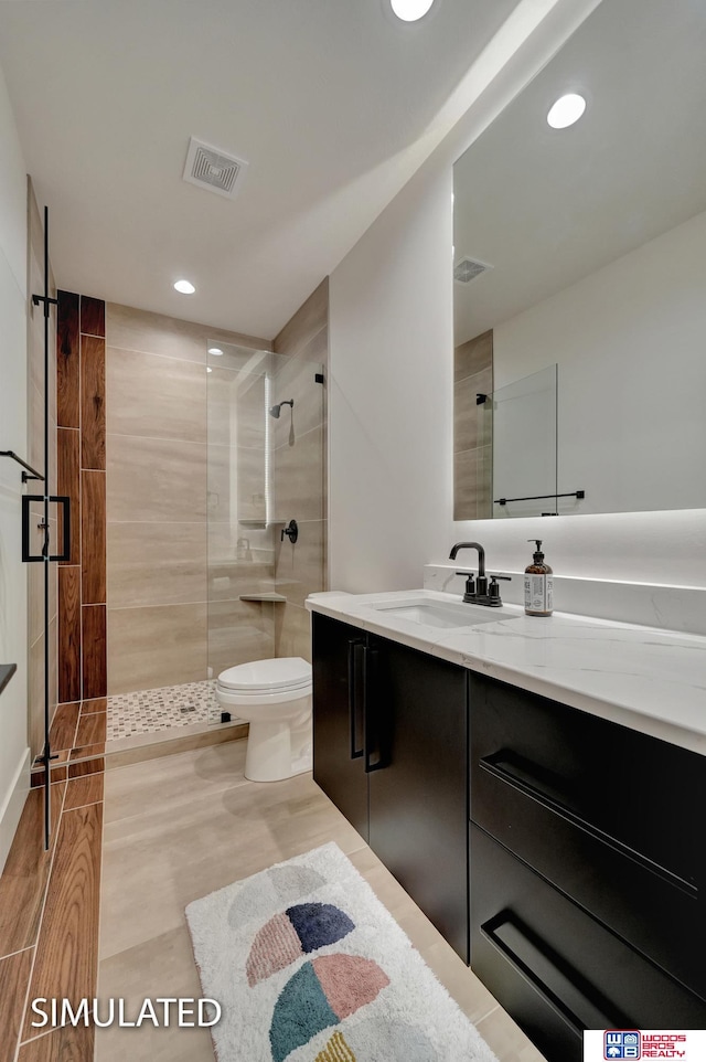 bathroom featuring vanity, a tile shower, and toilet