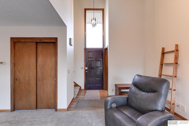 carpeted foyer entrance featuring a textured ceiling, a high ceiling, and an inviting chandelier