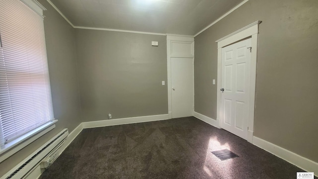 carpeted empty room with crown molding and a baseboard heating unit