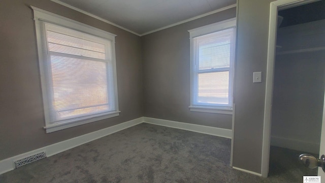 spare room featuring dark colored carpet and ornamental molding