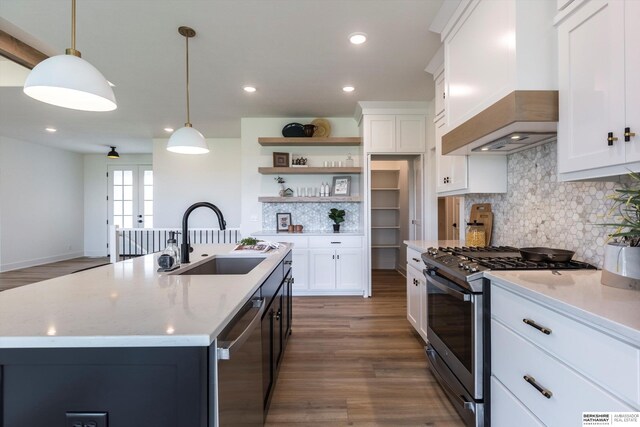 kitchen featuring dark wood-type flooring, sink, decorative light fixtures, custom range hood, and stainless steel appliances