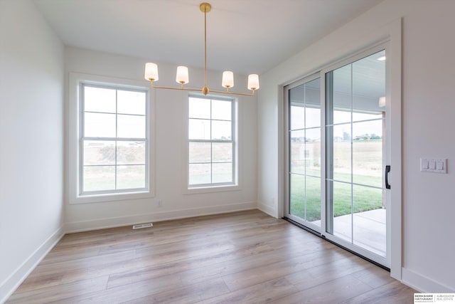 unfurnished dining area with a chandelier, light hardwood / wood-style flooring, and plenty of natural light