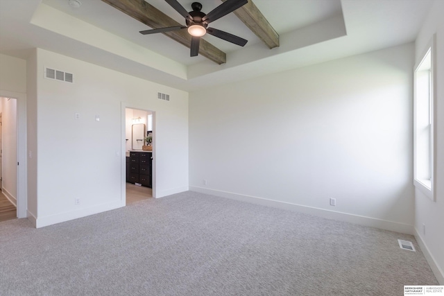 unfurnished bedroom with light carpet, ensuite bathroom, ceiling fan, and a tray ceiling