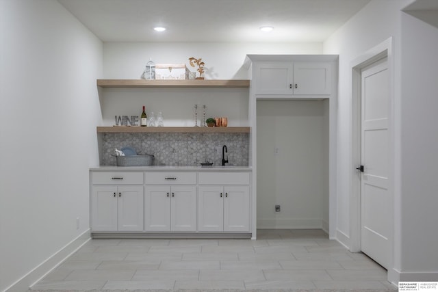 bar with white cabinetry, sink, and tasteful backsplash