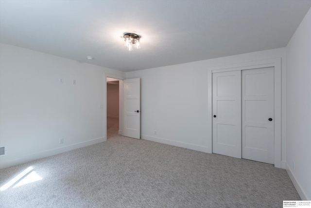 unfurnished bedroom with light colored carpet and a closet