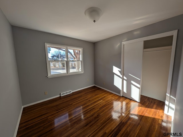 unfurnished bedroom featuring dark wood-type flooring and a closet