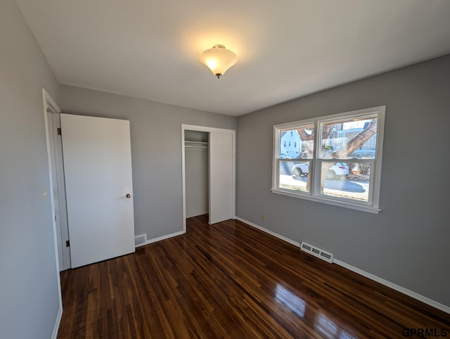 unfurnished bedroom with dark hardwood / wood-style flooring and a closet