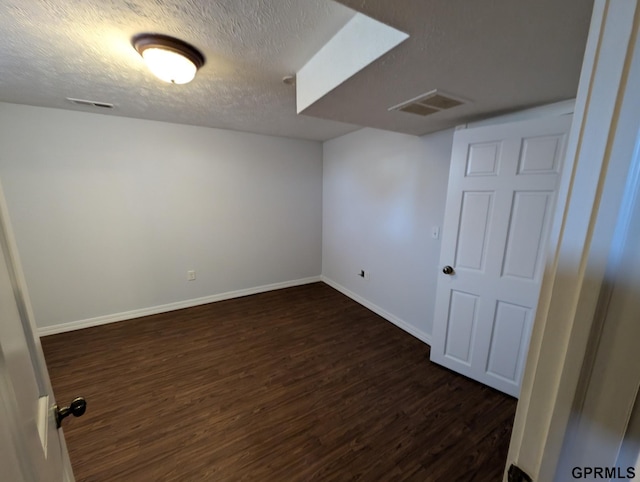 basement with a textured ceiling and dark hardwood / wood-style flooring