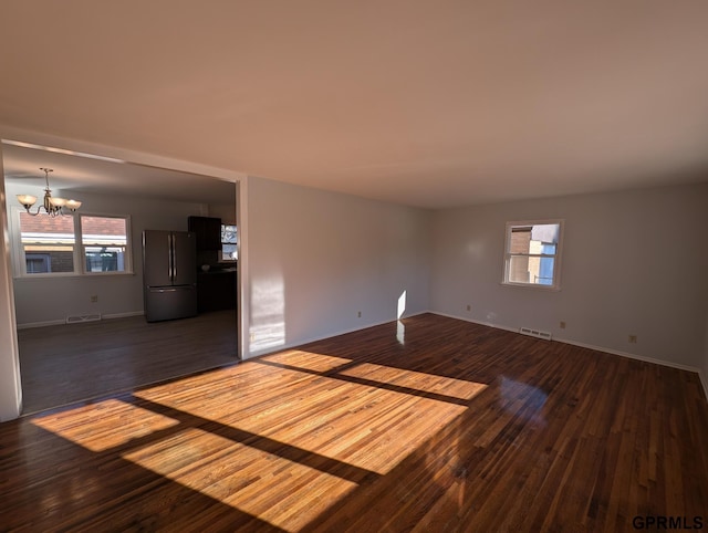 unfurnished room featuring dark hardwood / wood-style flooring, a healthy amount of sunlight, and a notable chandelier