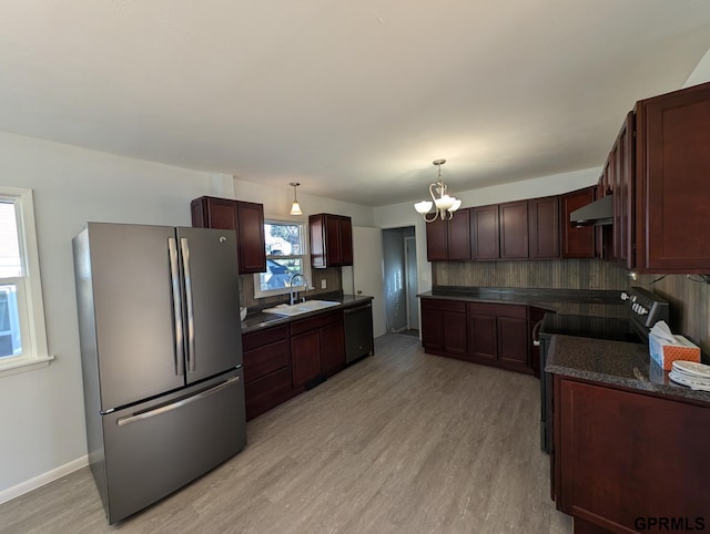 kitchen with extractor fan, sink, black appliances, decorative light fixtures, and light hardwood / wood-style floors