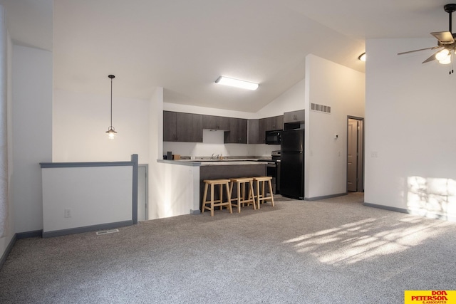 kitchen with black appliances, light colored carpet, kitchen peninsula, a kitchen bar, and dark brown cabinetry