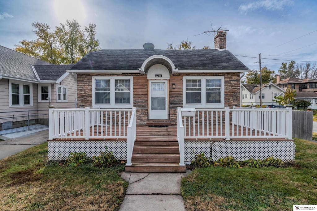 bungalow-style house featuring a wooden deck and a front yard