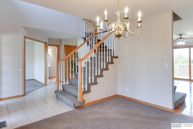 staircase with ceiling fan with notable chandelier and carpet floors