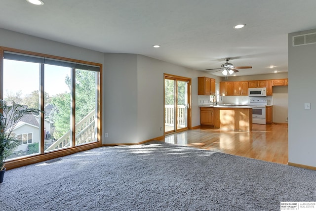 kitchen with a wealth of natural light, light hardwood / wood-style flooring, ceiling fan, and white appliances