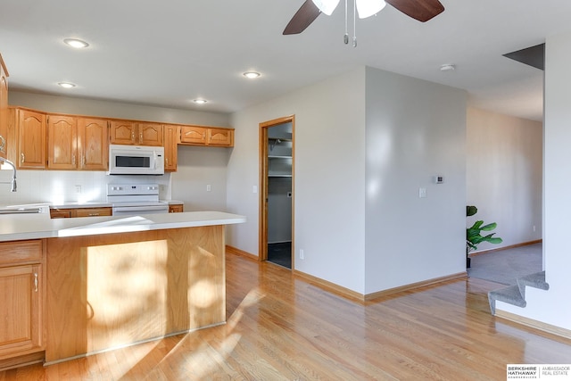 kitchen with light wood-type flooring, tasteful backsplash, white appliances, ceiling fan, and sink