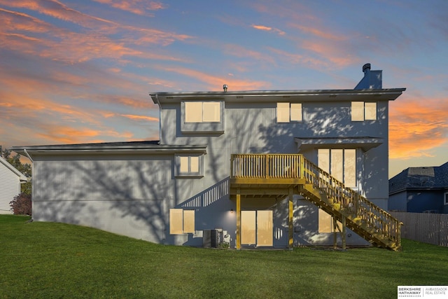 back house at dusk featuring a lawn, central air condition unit, and a deck