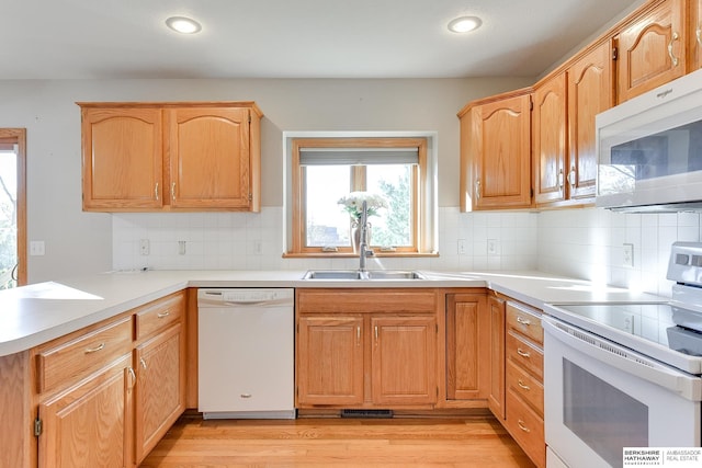 kitchen with white appliances, sink, light brown cabinetry, tasteful backsplash, and light hardwood / wood-style floors