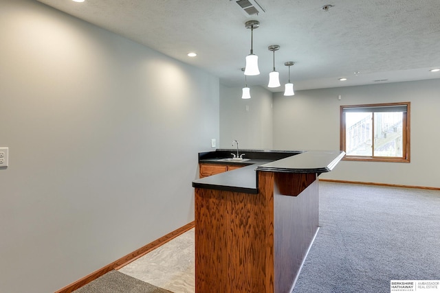 kitchen featuring a textured ceiling, light colored carpet, and hanging light fixtures