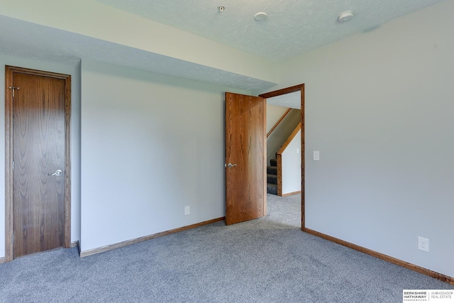 spare room with a textured ceiling and light carpet