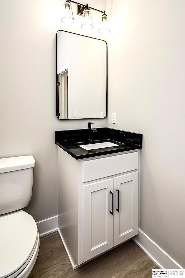 bathroom featuring toilet, vanity, and hardwood / wood-style flooring