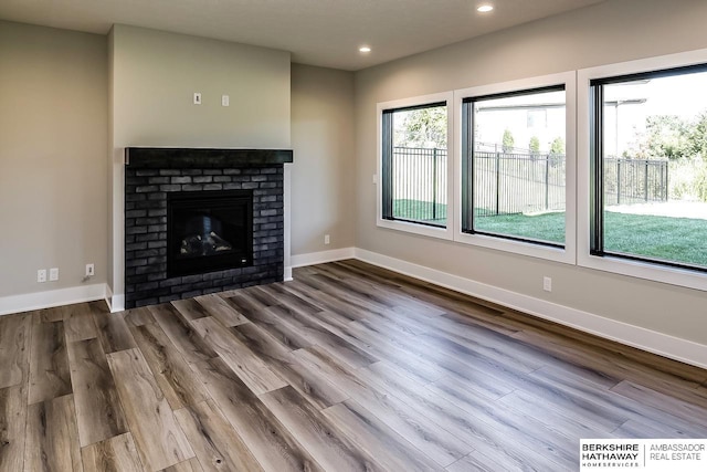 unfurnished living room with hardwood / wood-style floors and a brick fireplace