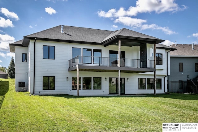 back of property featuring central AC unit, a balcony, and a yard